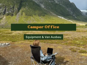 Camper Office - Equipment & Van Ausbau. Frau sitzt in Campingstuhl mit Laptop auf dem Schoß. Bergkulisse ist im Hintergrund zu sehen.