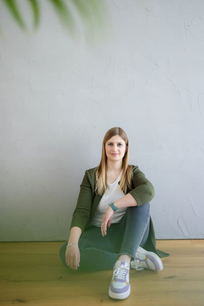 Marieluise sitzt an eine Betonwand gelehnt und schaut in die Kamera. Bereit für die Markenanalyse.